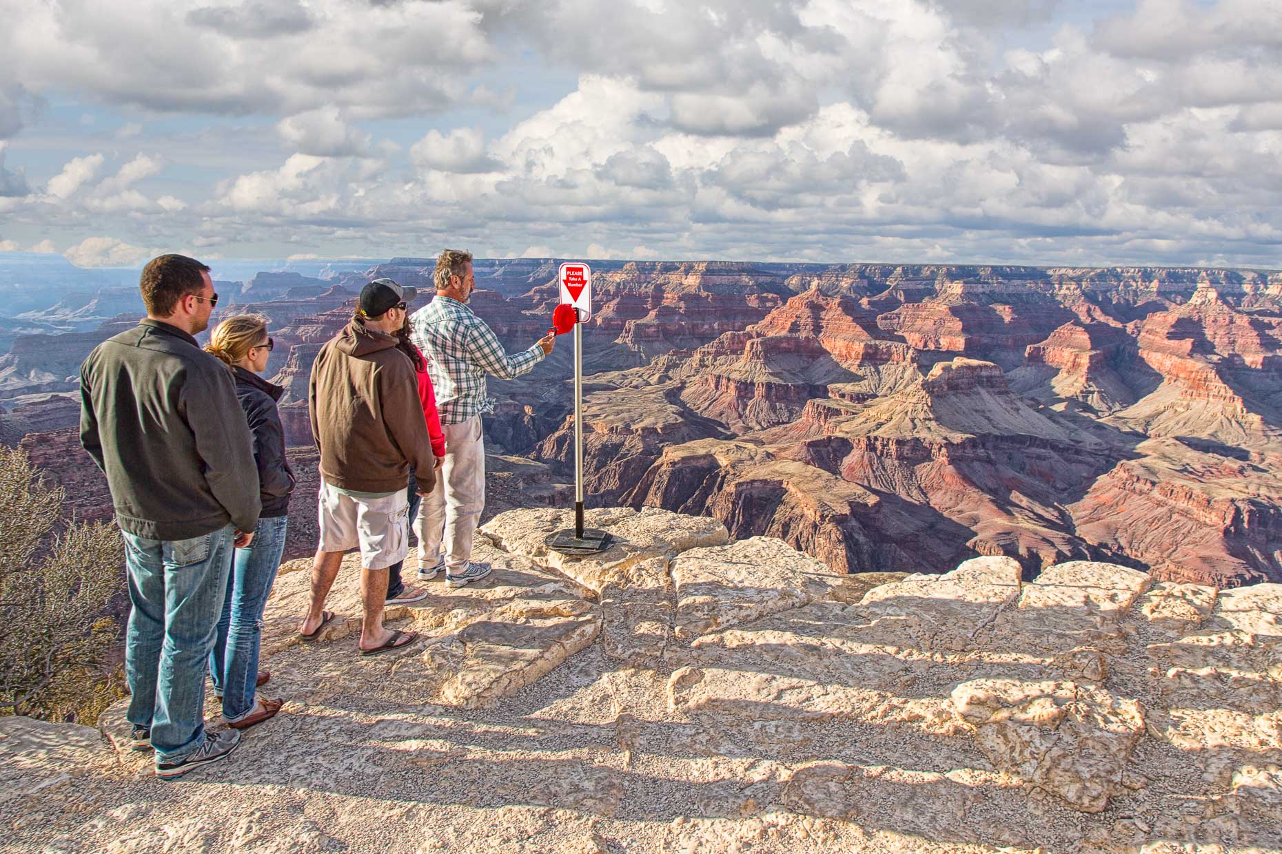 People wait in line to take a number from ticket machine at edge of the Grand Canyon.