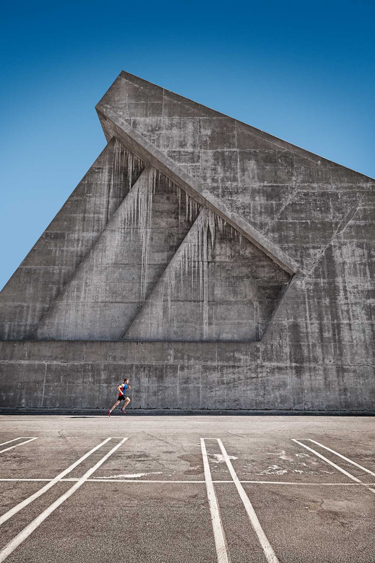 Man running against geometrically formed shaped concrete wall by David Zaitz Photography.