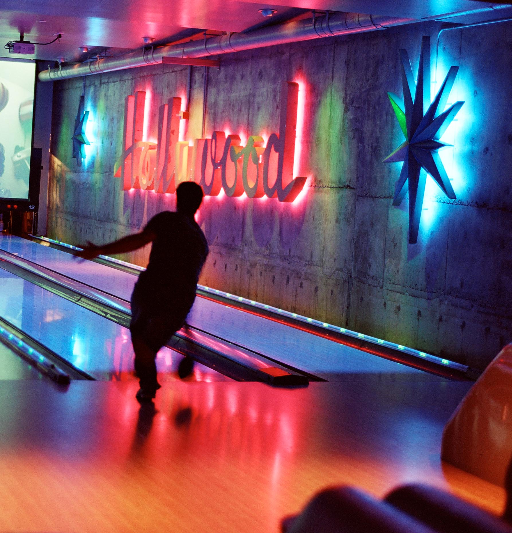 Man bowling in bowling alley with HOLLYWOOD sign on wall by David Zaitz
