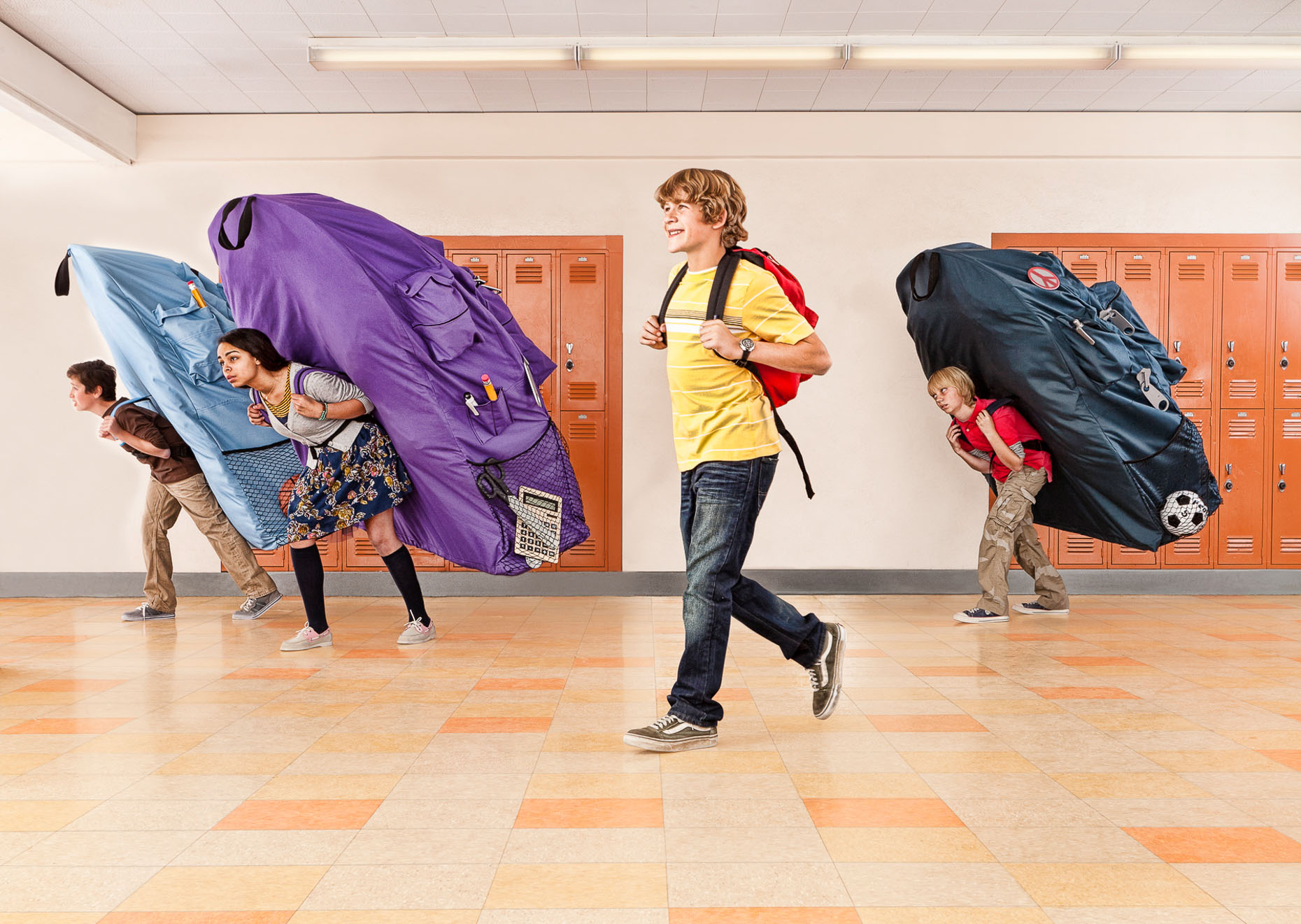 boy with normal sized book bag is smiling while other students are burdened with oversized book bags by David Zaitz