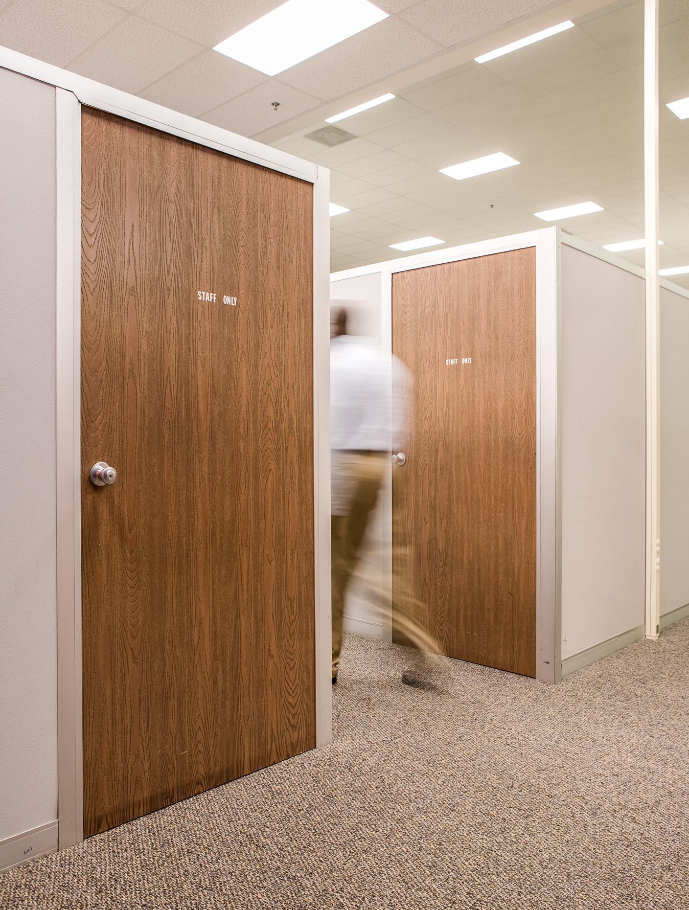 Man walking in office hallway with OFFICE sign on door. Corporate. David Zaitz Photography.