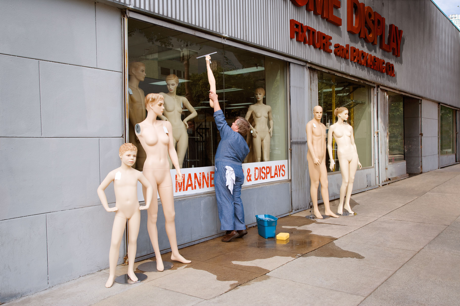 Man washing store windows uses mannequin arm to reach high. David Zaitz