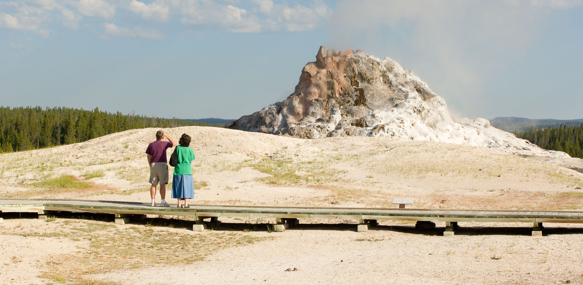 Man and woman standing on boardwalk waiting for geological geyser to erupt in Yellowstone National Park by David Zaitz
