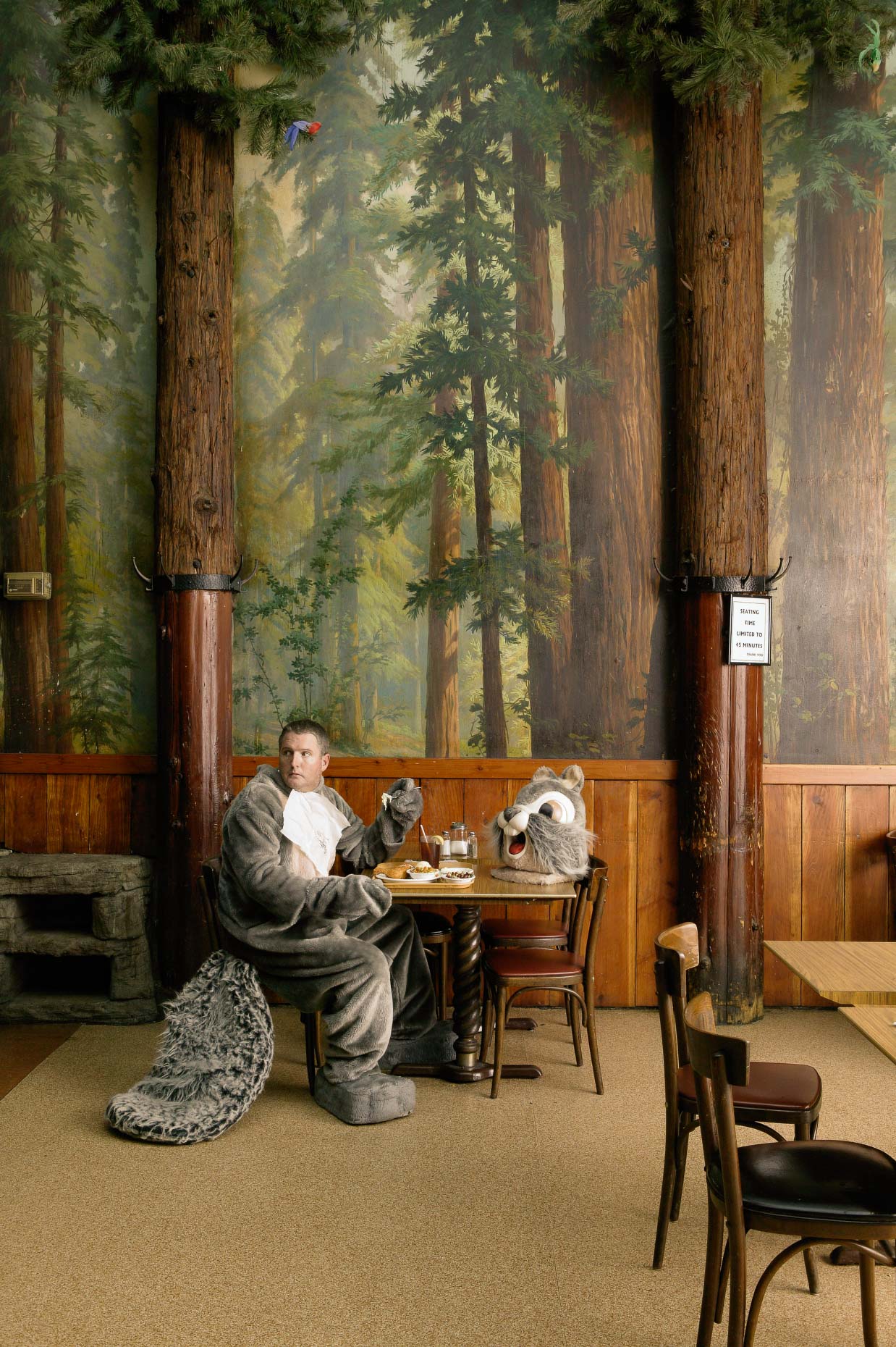 Man in squirrel costume having coffee in forest themed restaurant. David Zaitz.