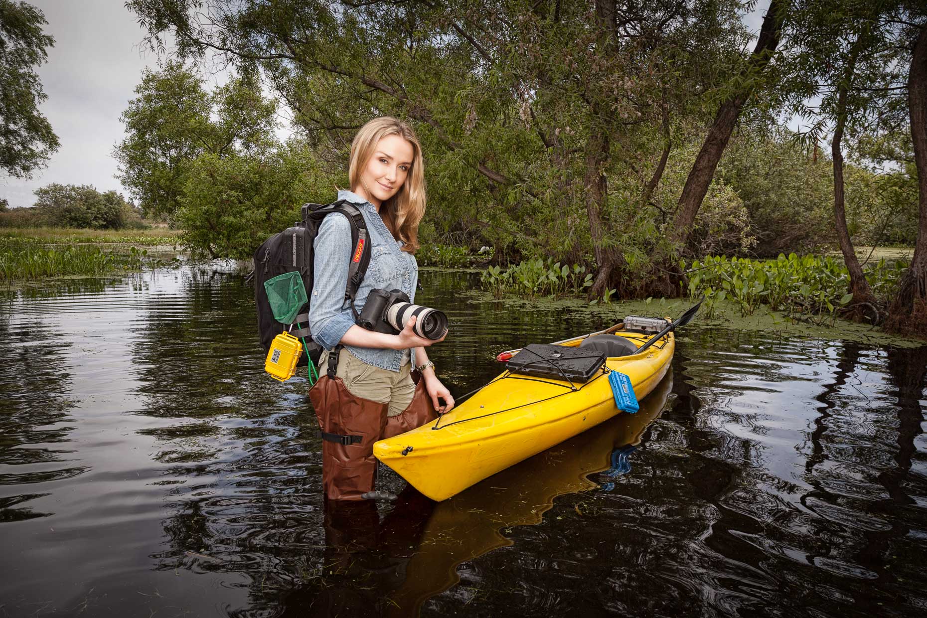 Portrait of woman with camera and kayak standing in water in wetlands. Torrance, California. David Zaitz Photography.