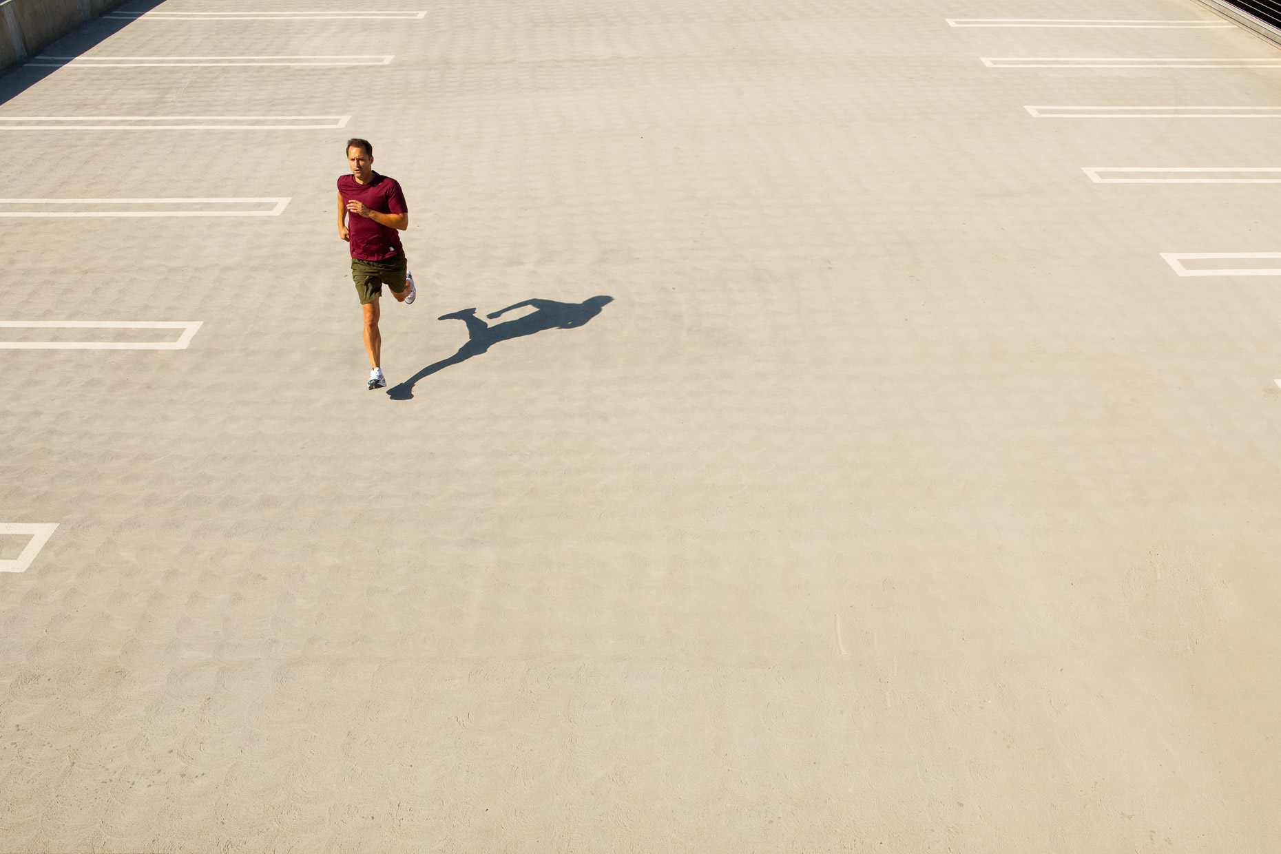 Man running on concrete paved parking lot, aerial by David Zaitz Photography.