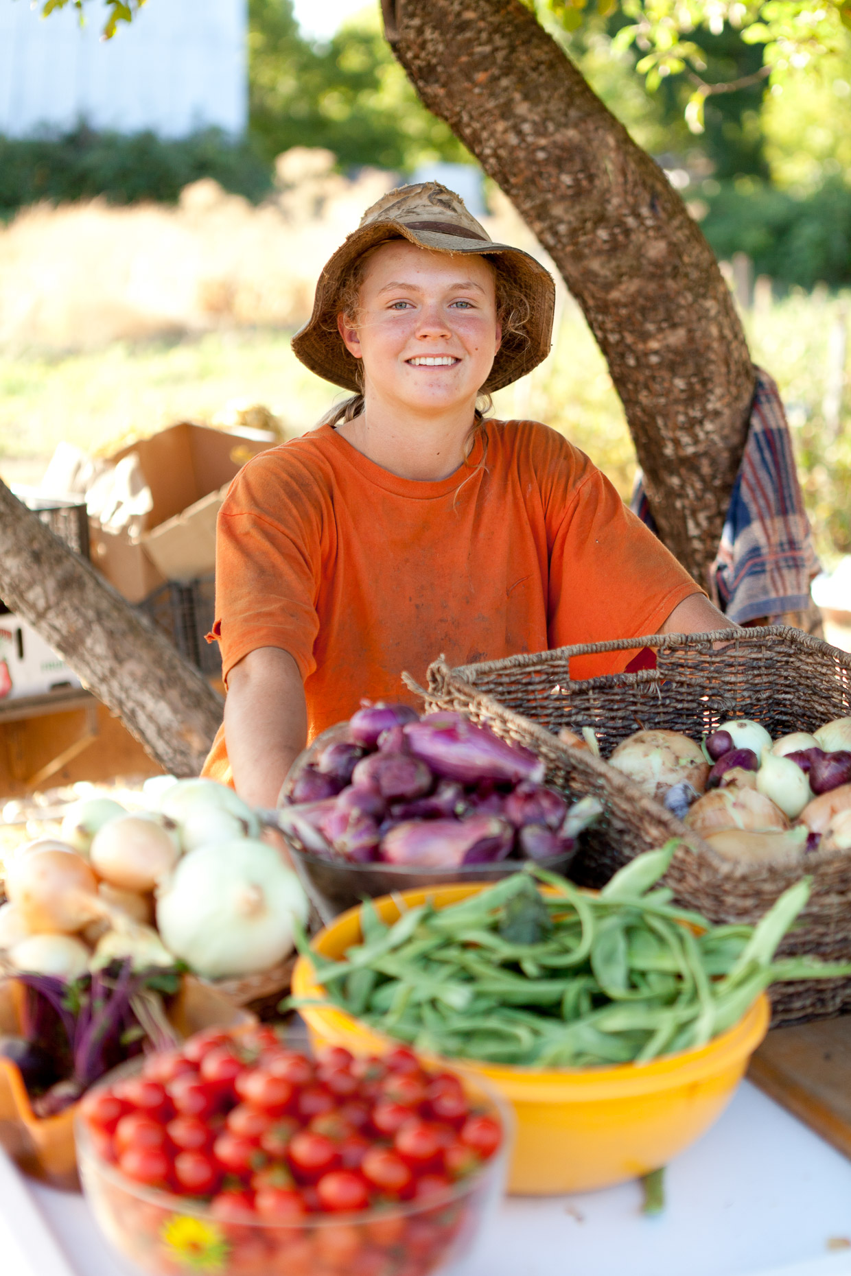 Portrait of girl wearing hat tending roadside produce and fruit stand in Applegate Valley, Oregon by David Zaitz