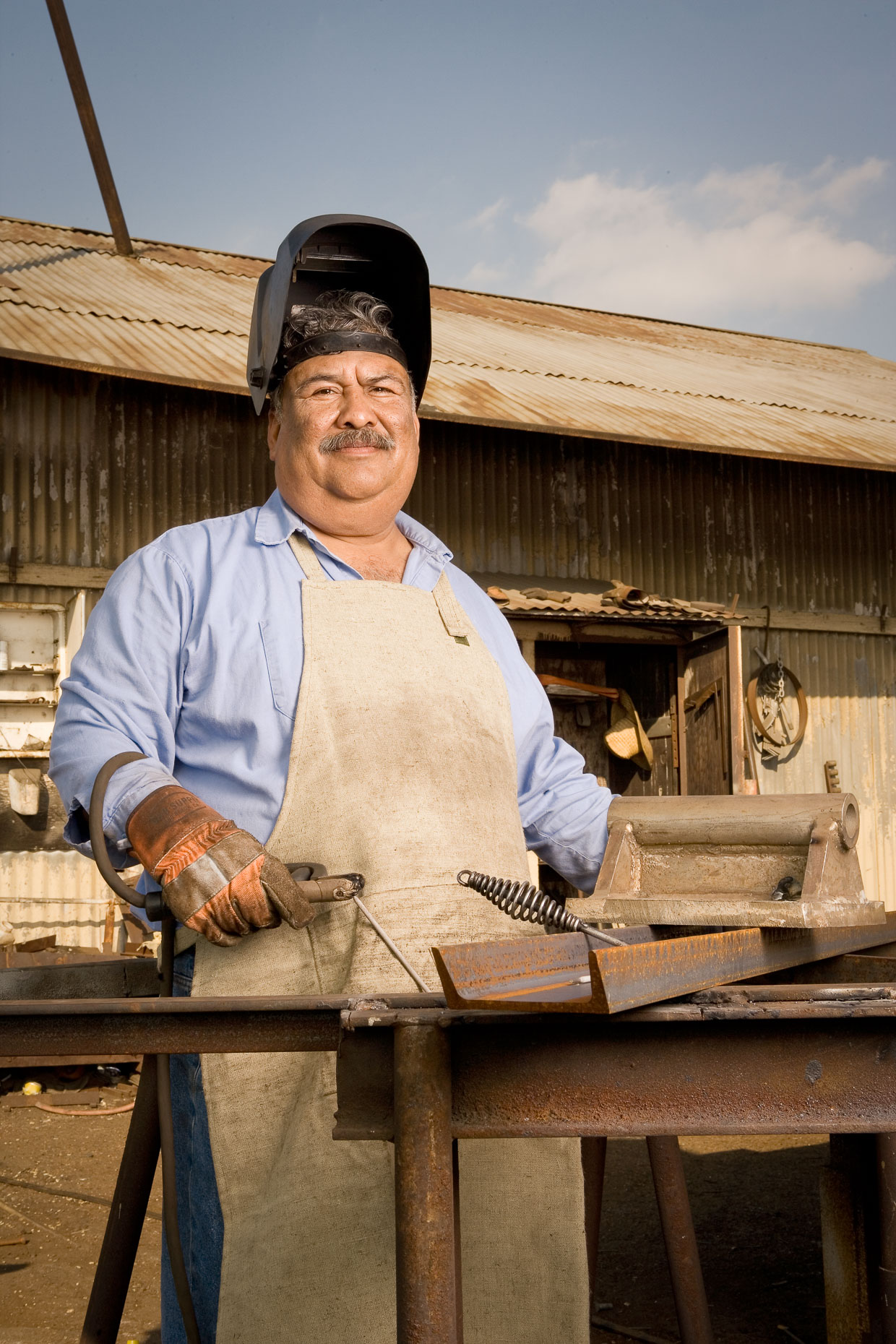 Environmental portrait of welder worker in iron works setting by David Zaitz