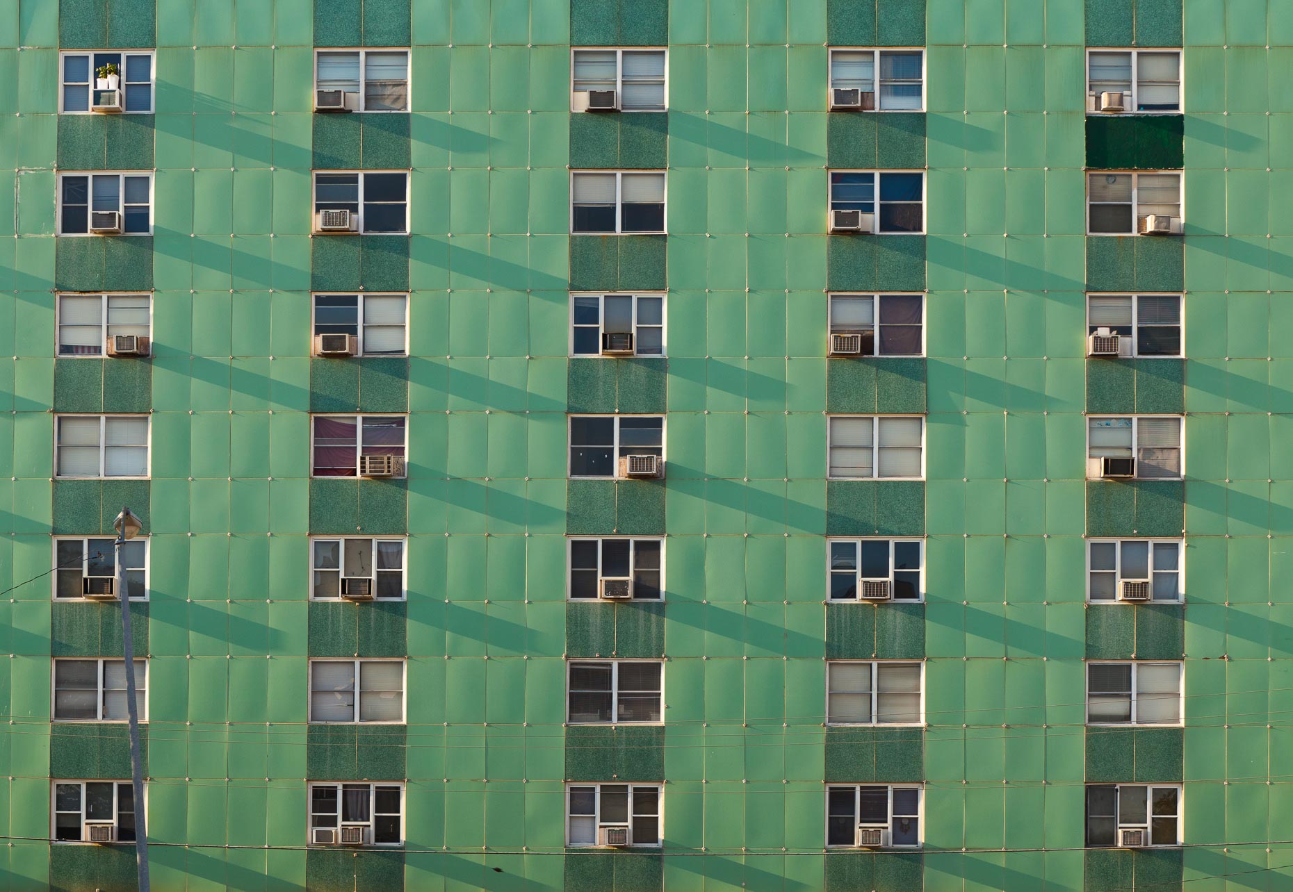 Green apartment building with windows and air conditioners by David Zaitz