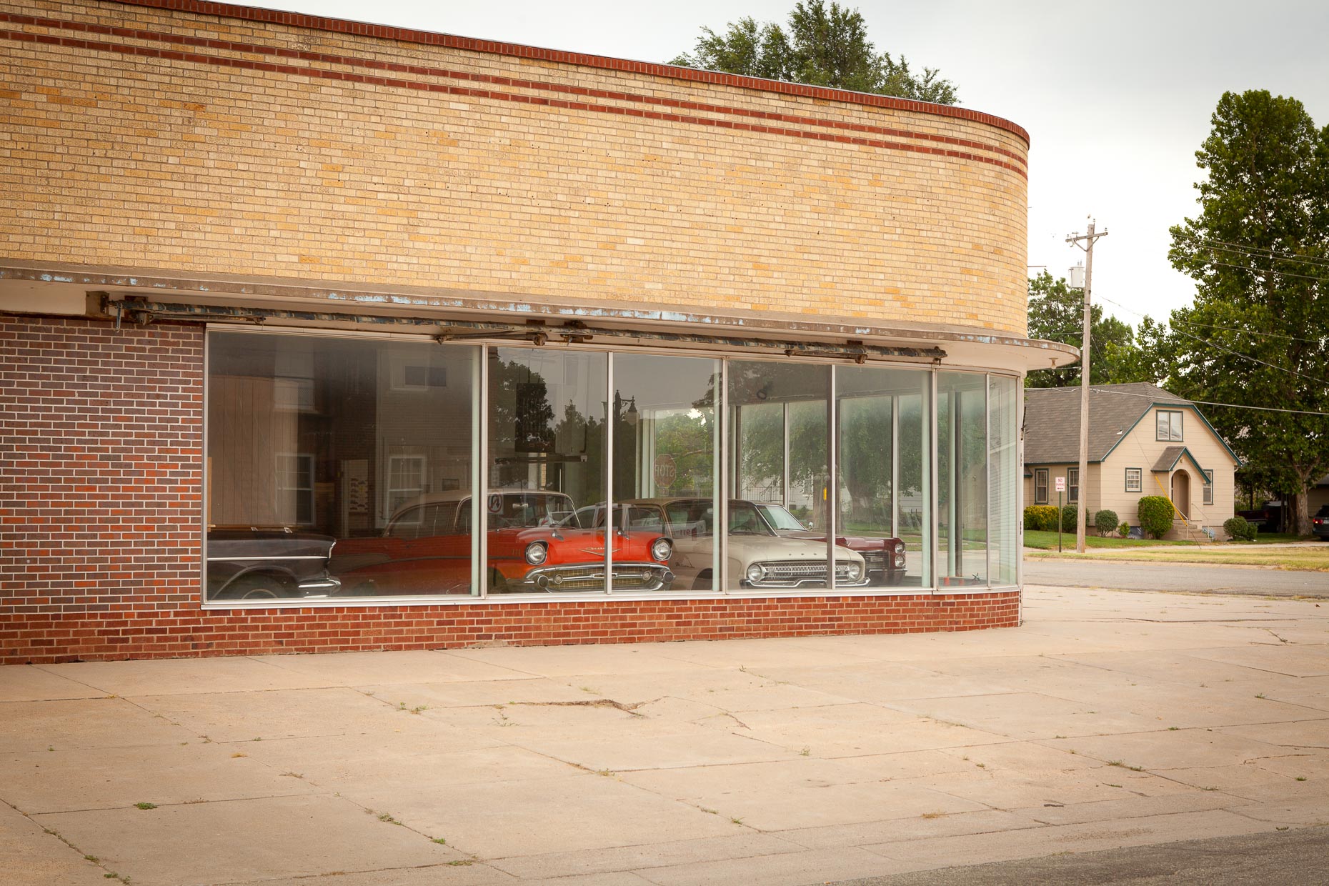 Cars in brick building showroom window by David Zaitz