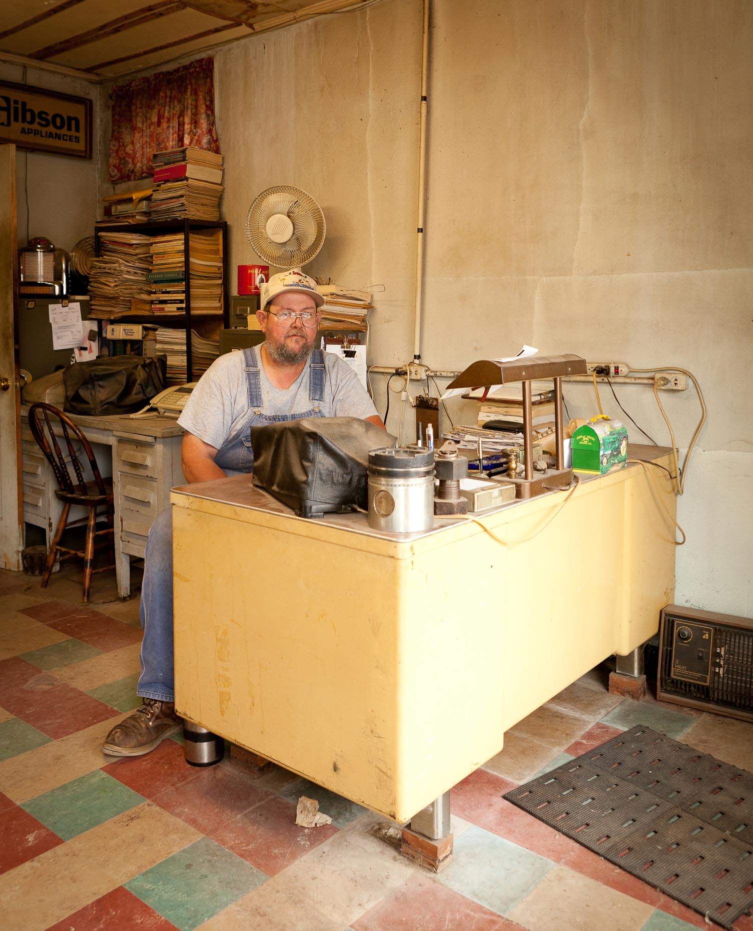 Portrait of appliance repair man sitting at desk in office by David Zaitz