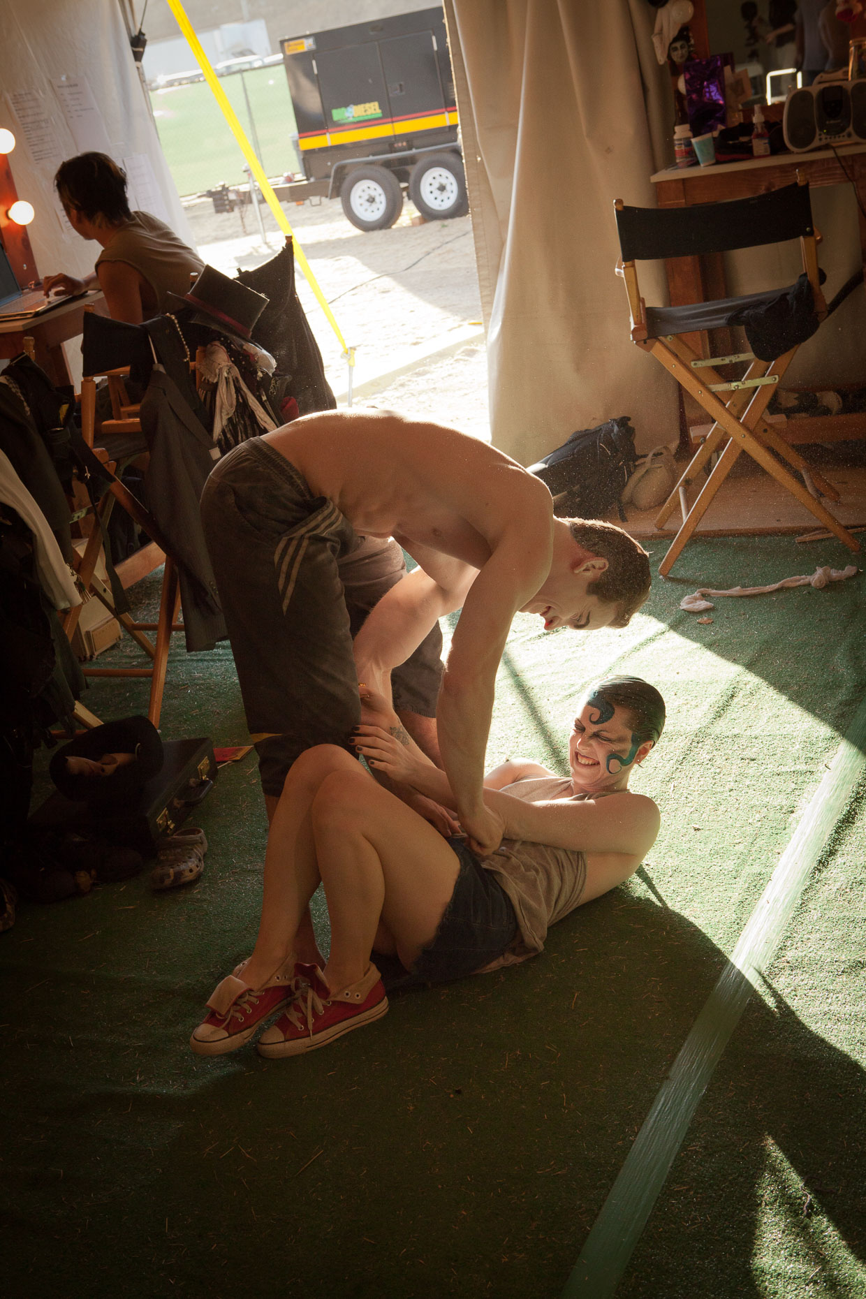 Performers in makeup tickle each other backstage at Cirque Berzerk circus performers, by David Zaitz