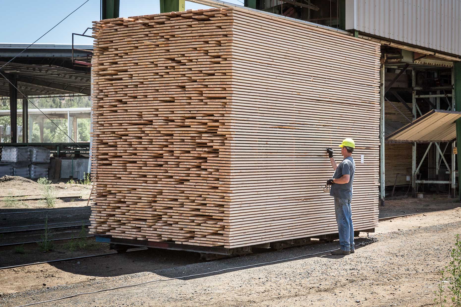 Man in hard hat writing on stack of lumber, Malheur Lumber Company mill in John Day, Oregon by David Zaitz.