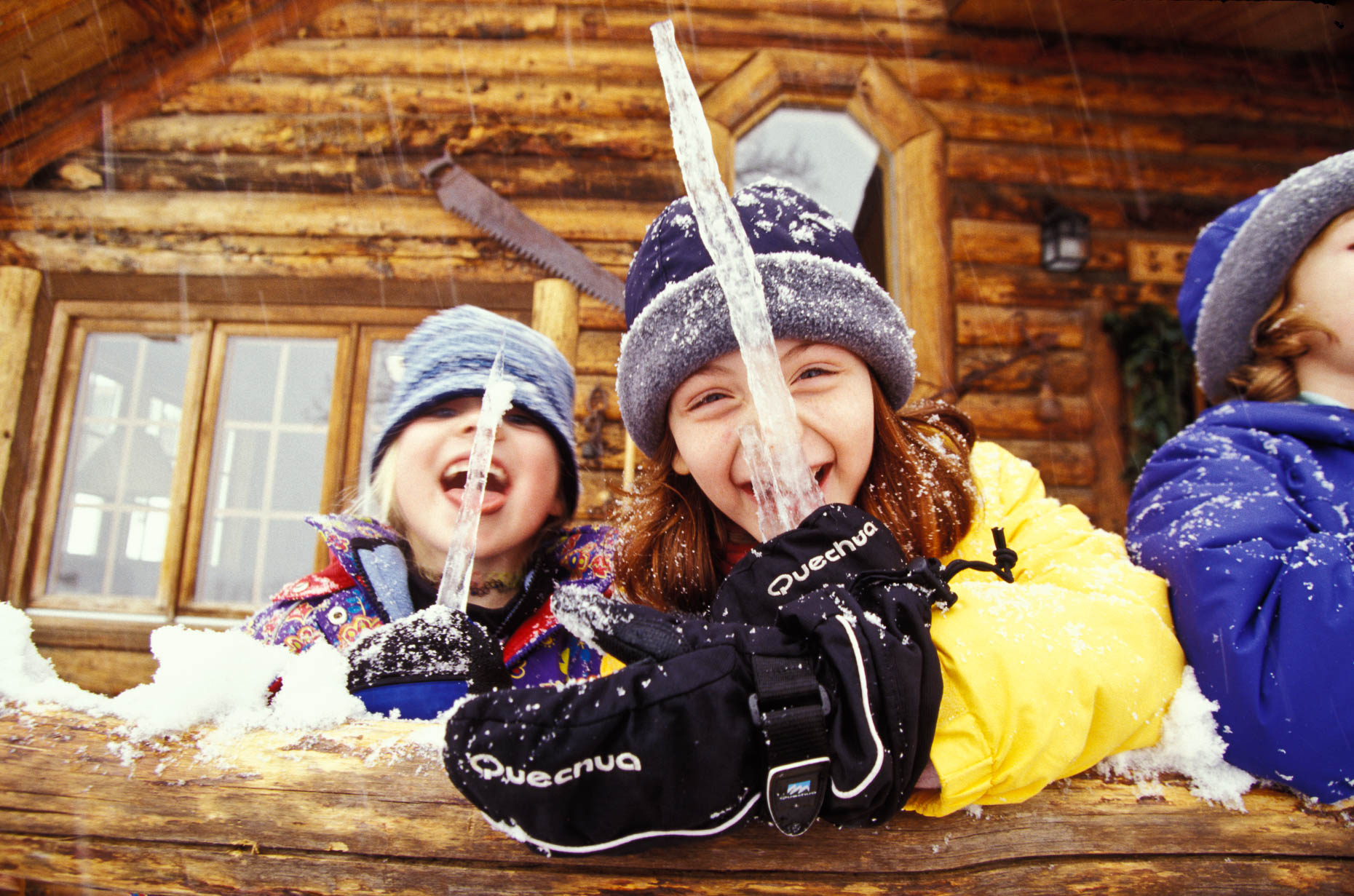 Girls licking icicle on porch of cabin at Vista Verde Ranch, Colorado by David Zaitz