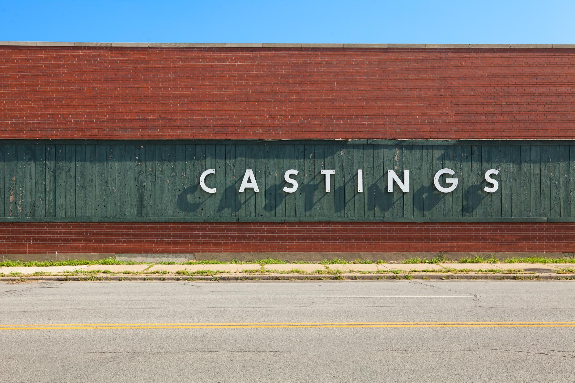 CASTINGS sign on side of green and brick building by David Zaitz