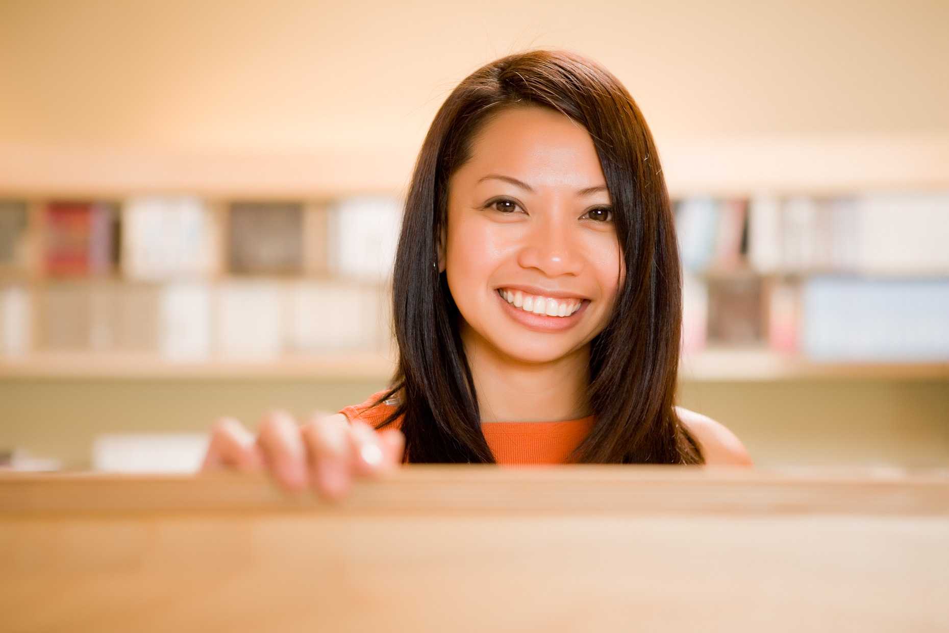 Portrait of woman in office environment looking over cubicle divider.